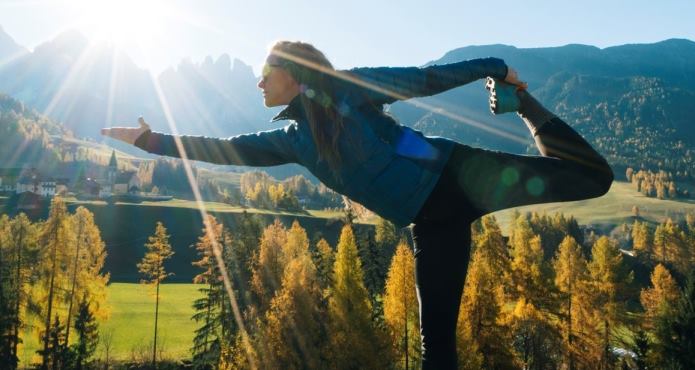Women practices yoga in the sunny mountains