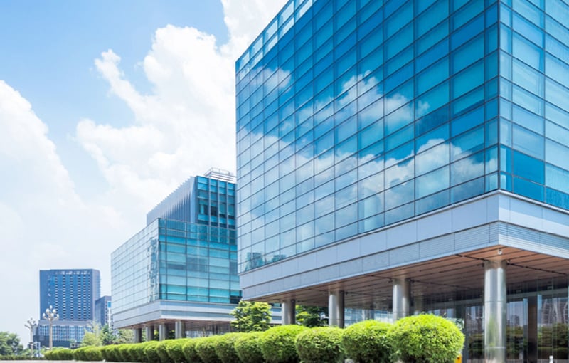 Glass office buildings with trees and blue sky background